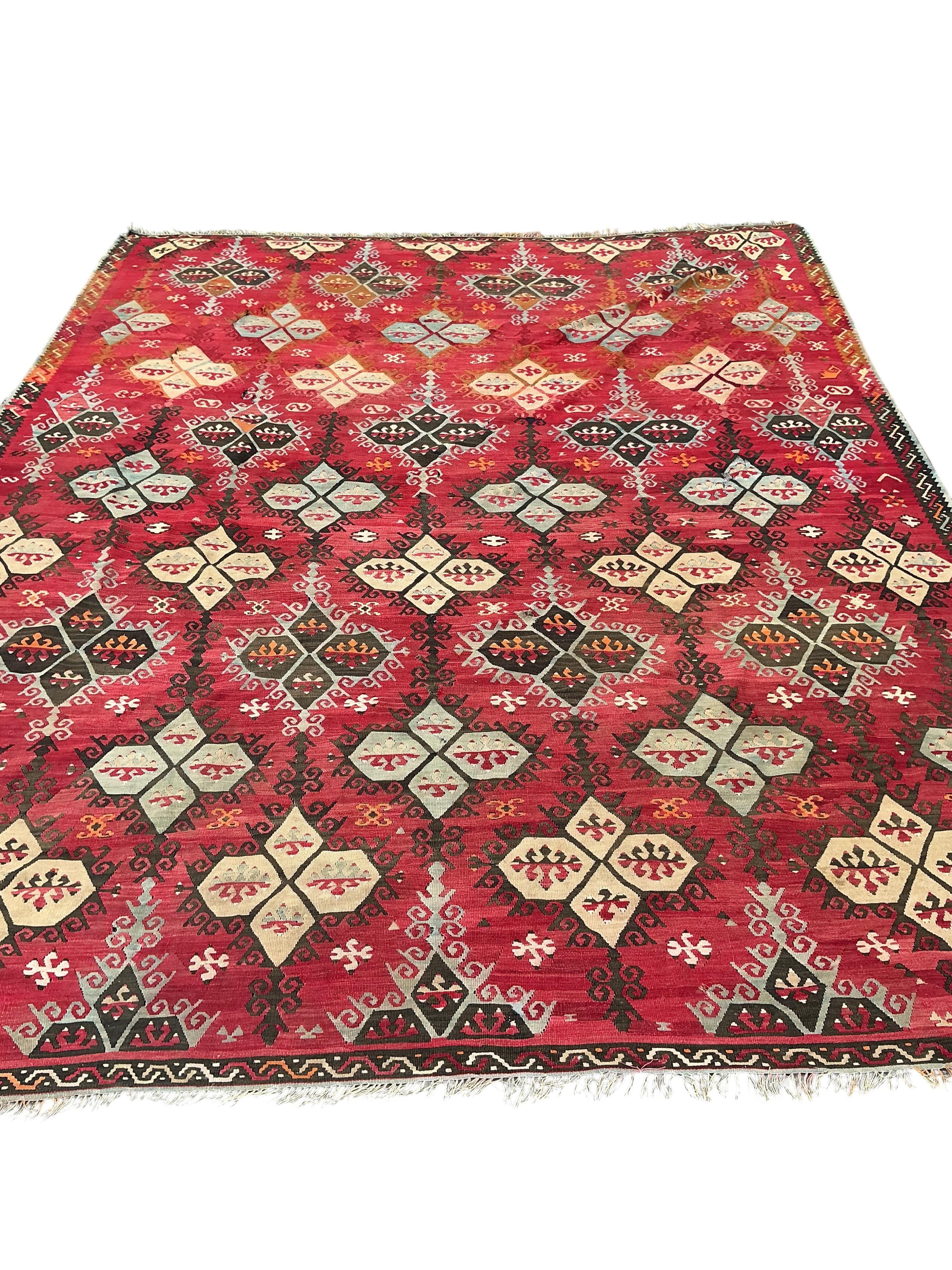 A Turkish Anatolian Kilim polychrome flatweave carpet, woven with geometric lozenges, on a pink field, 350 x 273cm